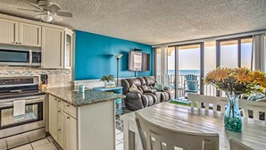 A kitchen with a microwave, oven, and a dining area with a table and chairs. - Beachfront Murrells Inlet Condo w/ Ocean Views (Murrells Inlet)