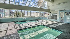An indoor swimming pool with a glass ceiling, safety signs, and a view of the outside. - Beachfront Murrells Inlet Condo w/ Ocean Views (Murrells Inlet)