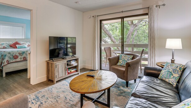 A room with a bed, a TV, a sofa, a chair, a table, and a balcony with a view. - 2 Blocks to Beach: Hilton Head Condo, Pool, Tennis (Hilton Head Island)