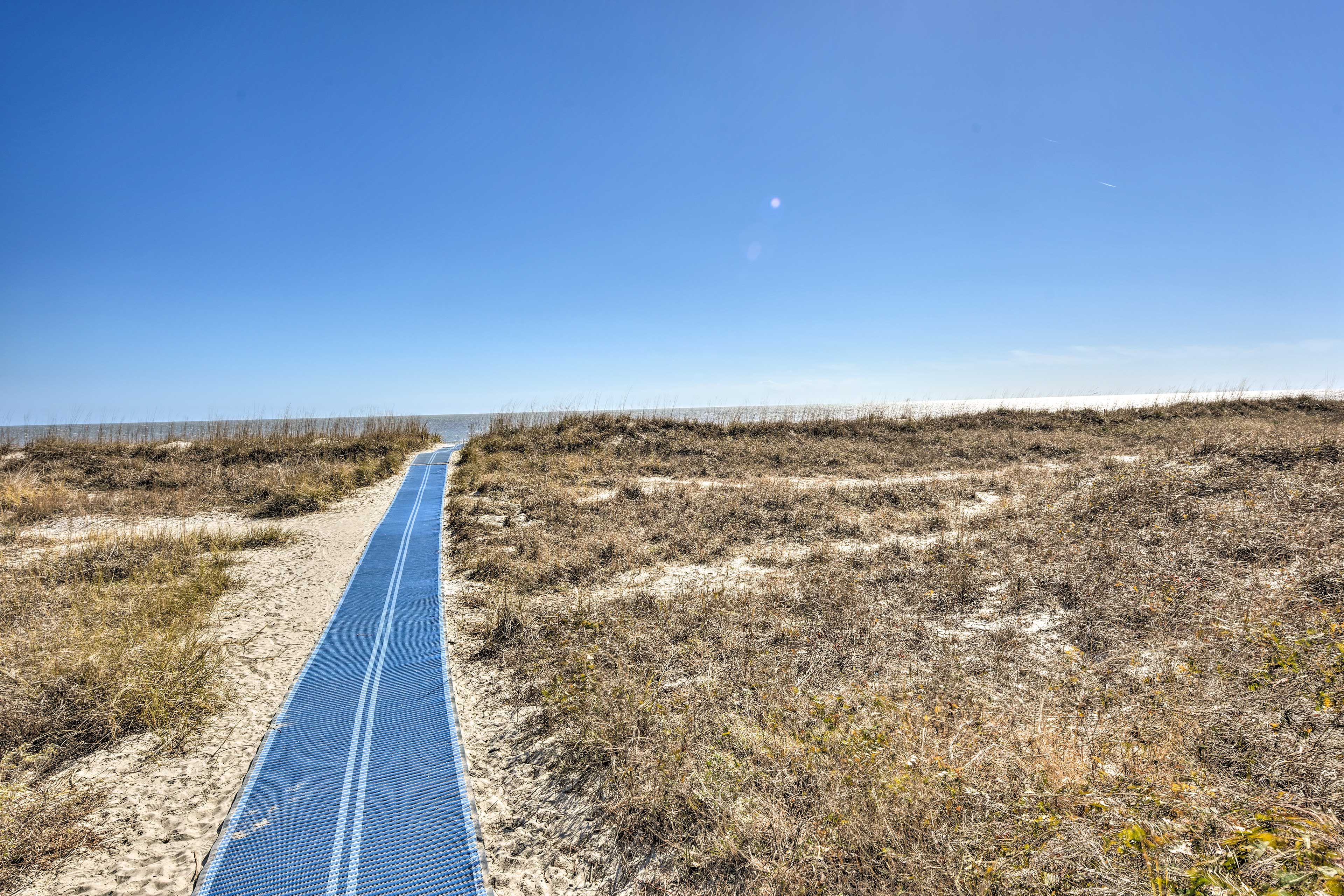 A pathway leading to a beach with a clear sky.