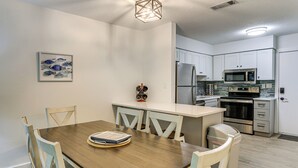 A modern kitchen with white cabinets, stainless steel appliances, and a wooden dining table with chairs. - 2 Blocks to Beach: Hilton Head Condo, Pool, Tennis (Hilton Head Island)