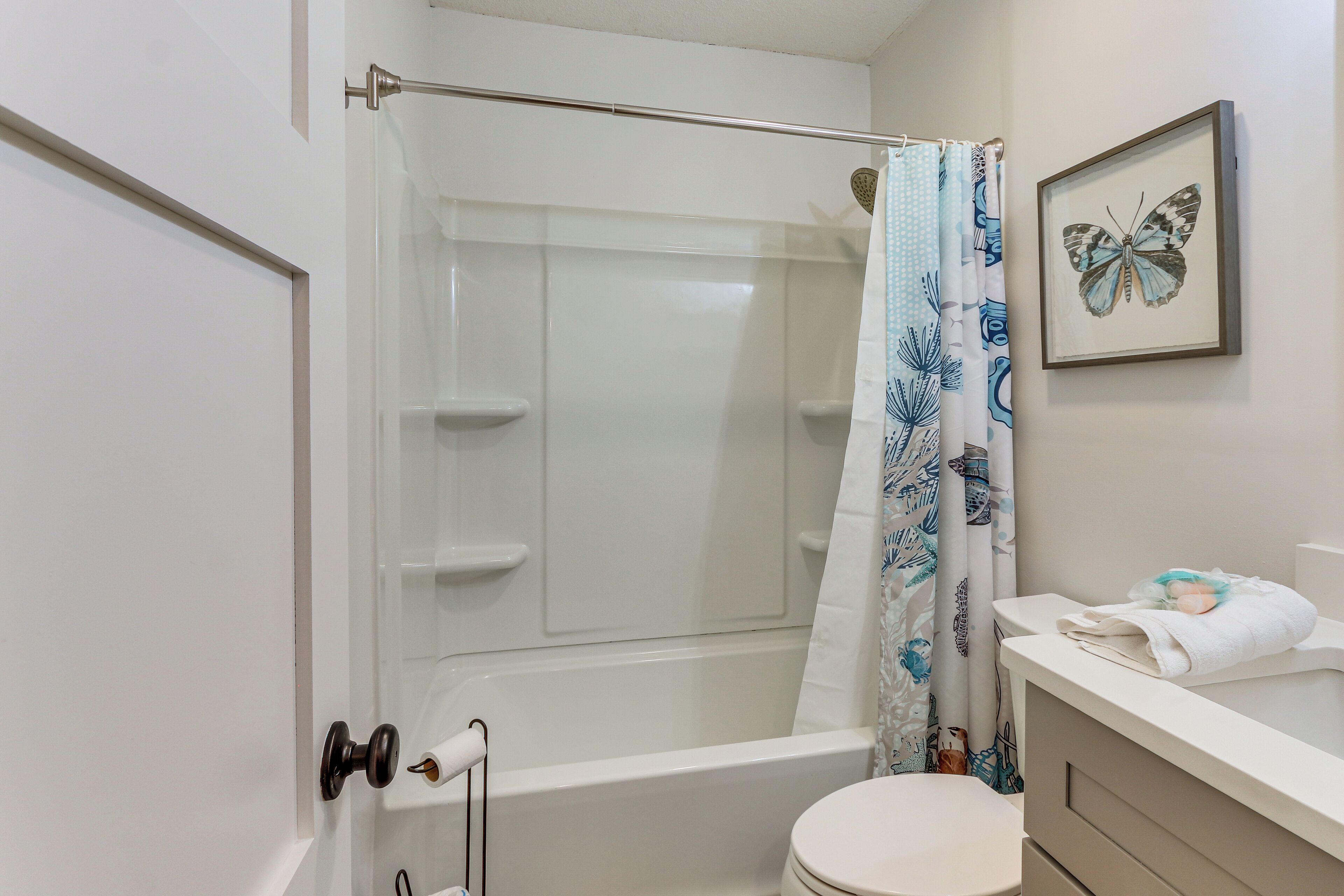 A bathroom with a bathtub, toilet, and a shower curtain.