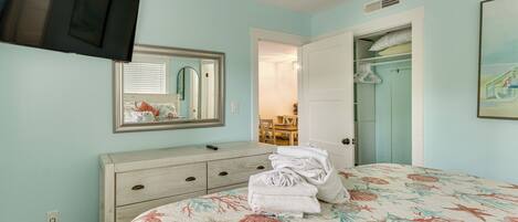 A bedroom with a bed, dresser, mirror, and closet.