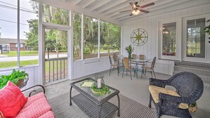 A covered porch with wicker furniture, a table with a vase, and a compass wall decoration.