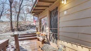 A wooden deck with steps leading to a porch, outdoor seating, and American flags.