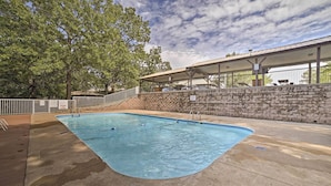 A swimming pool with a stone wall and a covered seating area. - Accessible Branson Condo: Balcony + Lake Access! (Branson West)