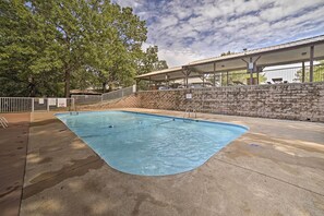 Una piscina con un muro in pietra e una zona relax coperta.
