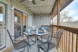 A covered patio with a table set for four, metal chairs, and a view of the surrounding landscape. - Branson Condo w/ Views - Near Silver Dollar City! (Branson West)