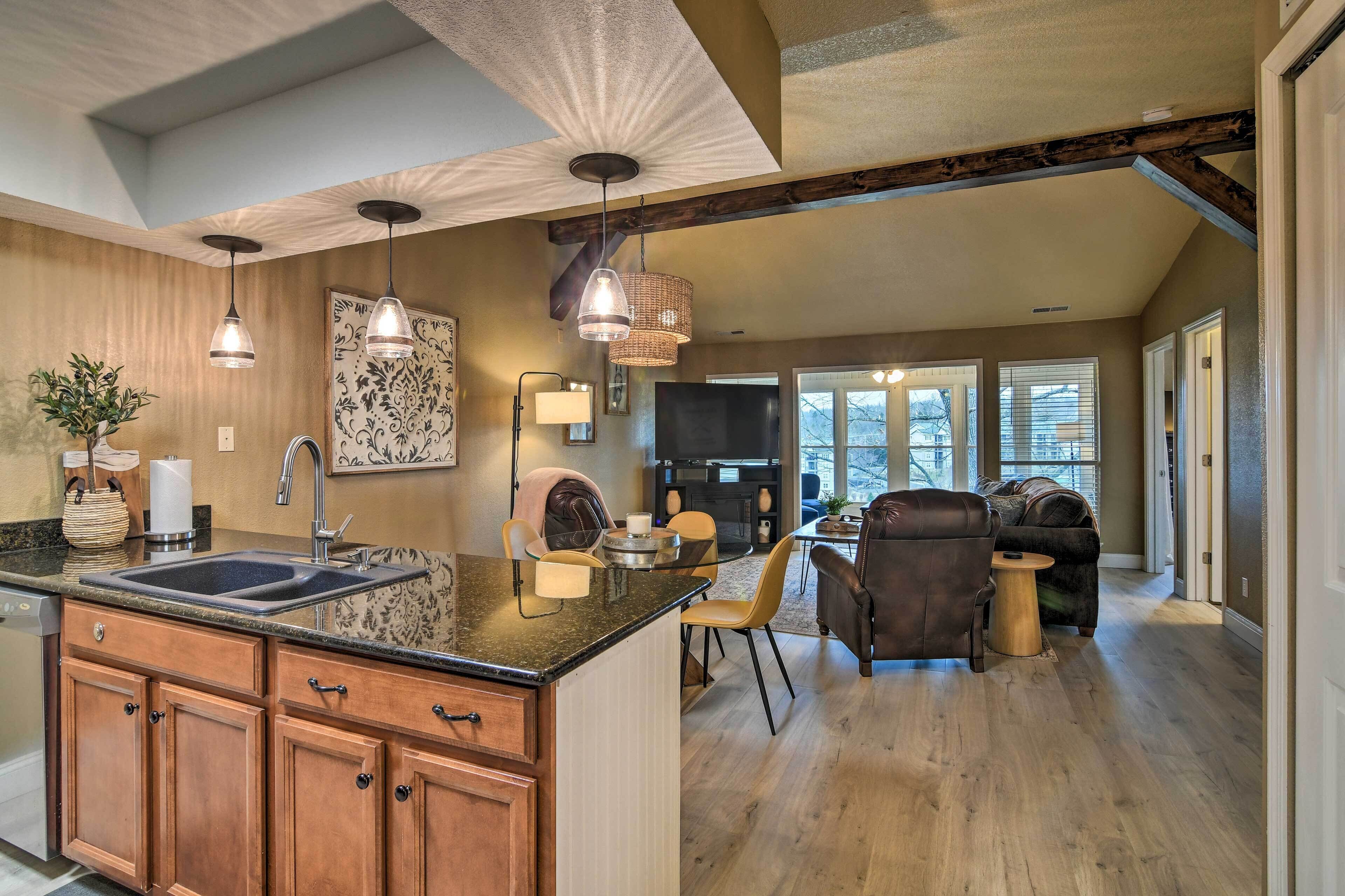 A spacious kitchen with a large island, wooden cabinets, and pendant lighting.