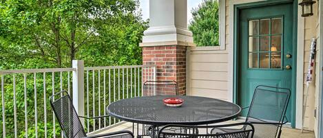 A covered patio with a round metal table and chairs, a brick fireplace, and a teal door.