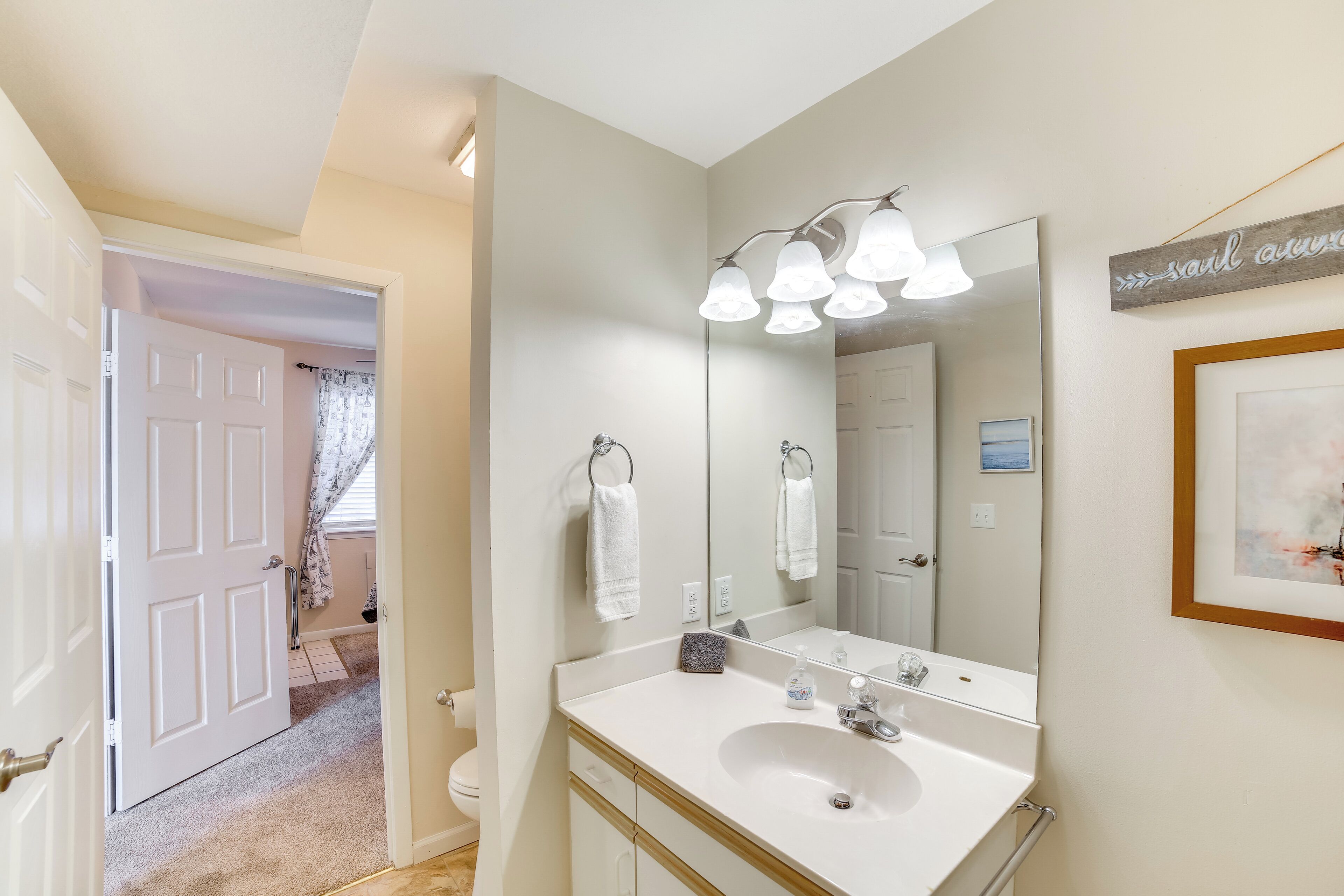 A bathroom with a white sink, a large mirror, and a towel rack.