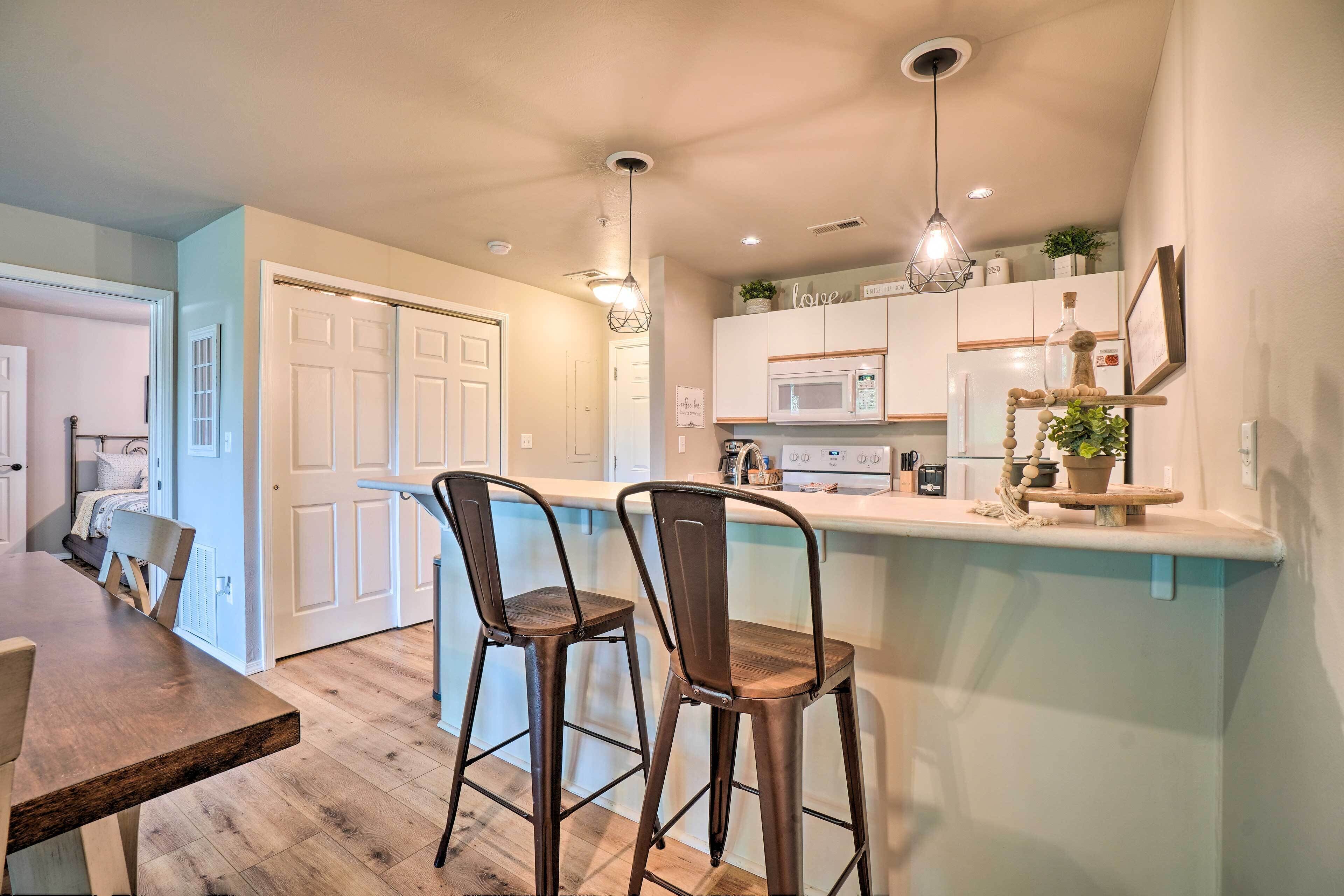 Una cocina moderna con una isla central, taburetes de bar e iluminación colgante.