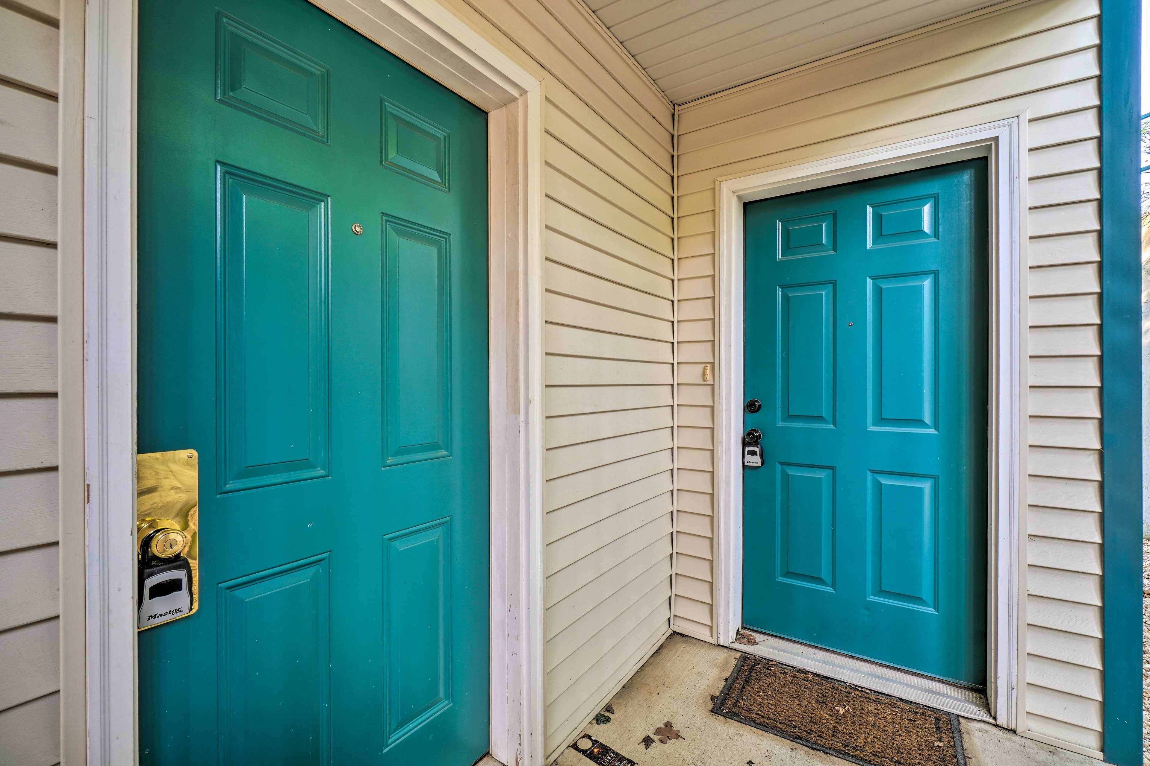 Une porte de couleur bleu-vert avec une fente à lettres en laiton et un paillasson devant l’entrée.