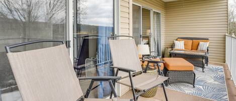 A covered patio with outdoor furniture, including chairs and a sofa, and a ceiling fan.