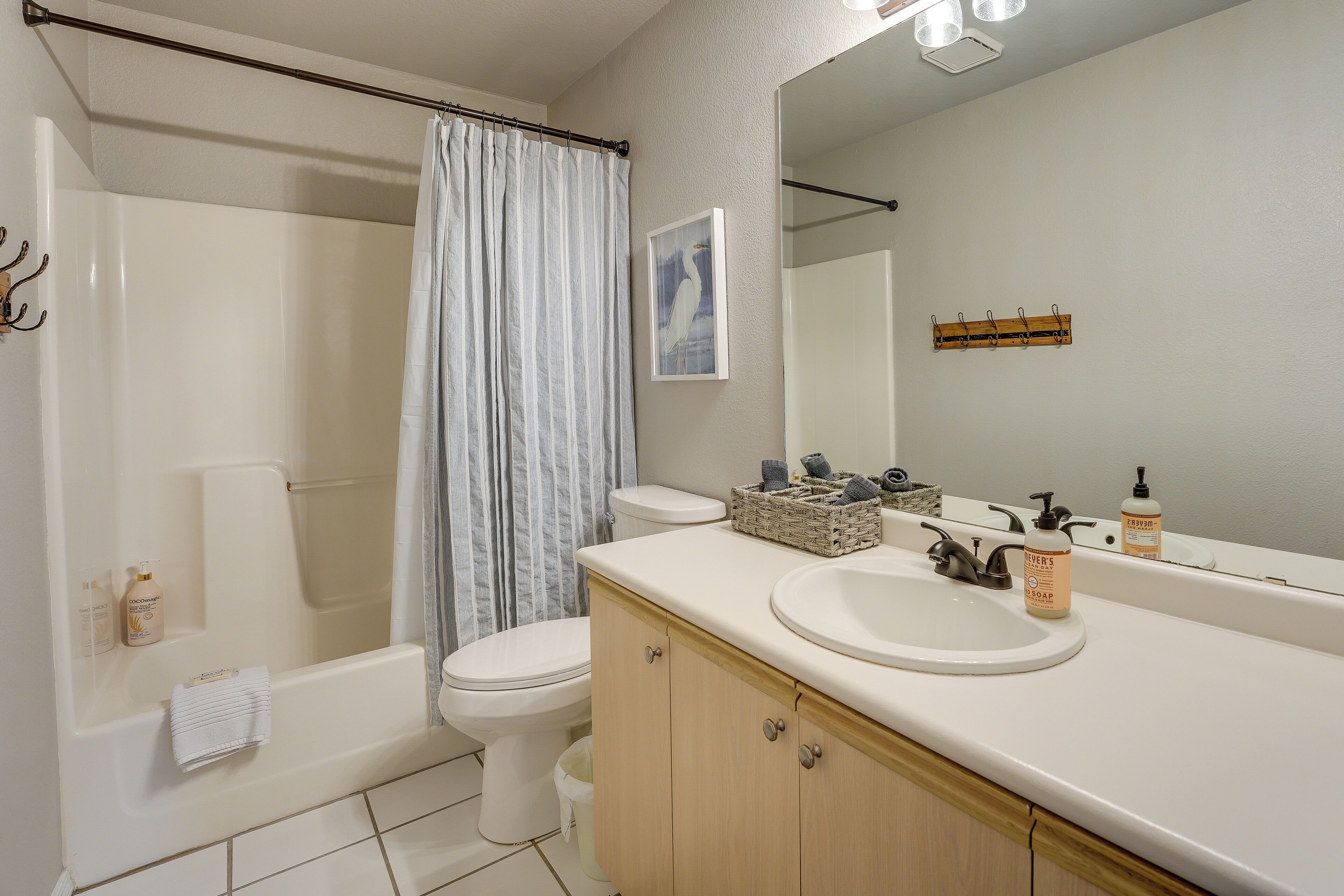 Ein Badezimmer mit Badewanne, Toilette und Waschbecken. Auf der Ablage des Waschbeckens liegen Pflegeprodukte und ein Handtuchhalter ist vorhanden.