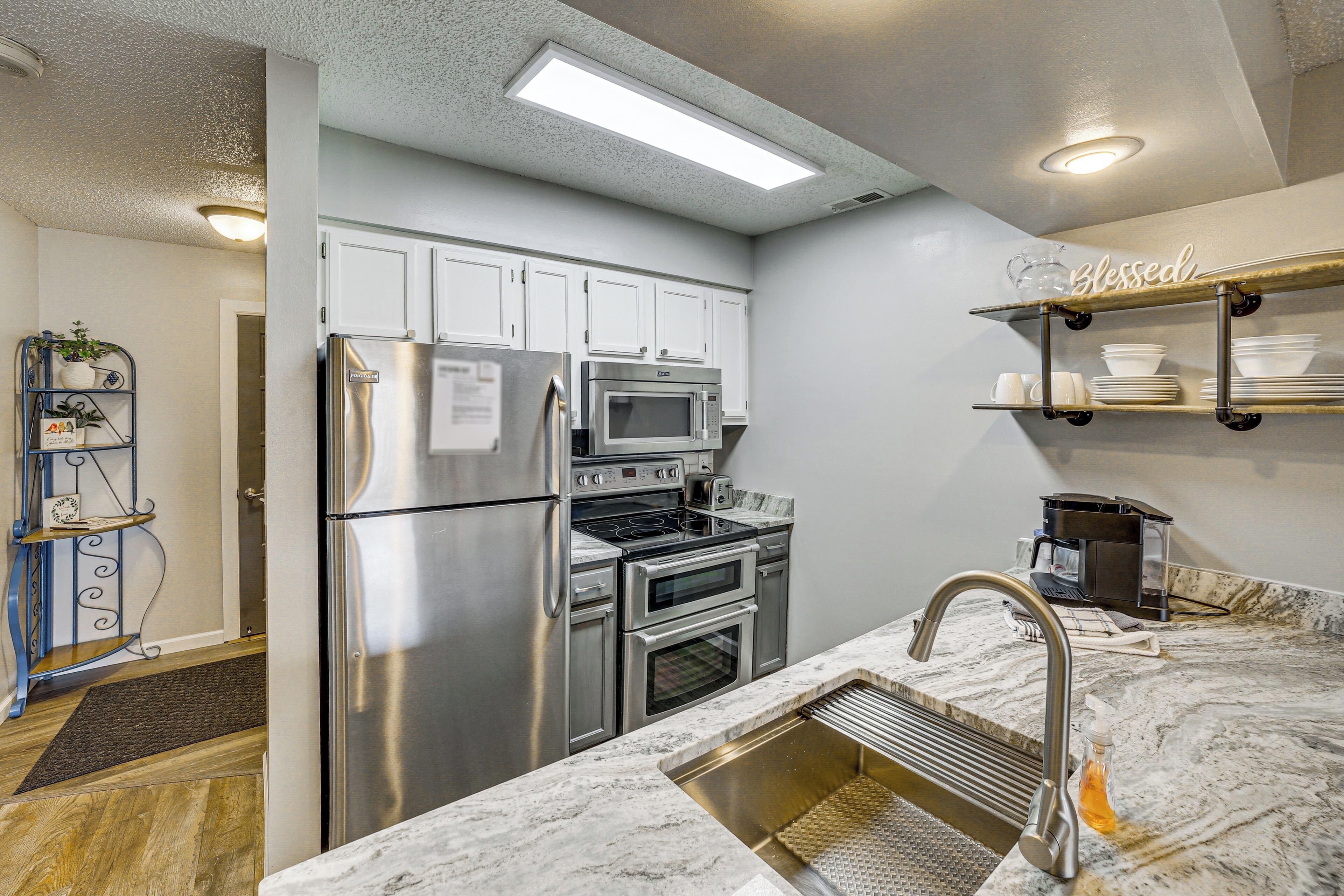 A modern kitchen with stainless steel appliances, a marble countertop, and a built-in oven.
