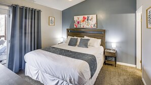 A bedroom with a large bed, a ceiling fan, a nightstand with a lamp, and a floral painting on the wall. - Family-friendly Condo: 1 Mi to Silver Dollar City! (Branson West)