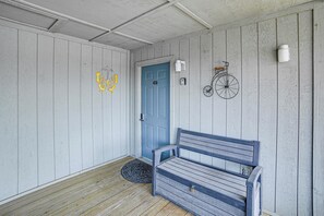 A wooden porch with a blue door, a bench, a bicycle, and a butterfly decoration.