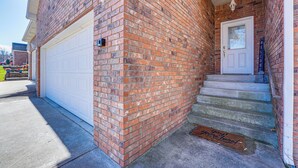 A residential building with a brick exterior, a white garage door, and a front door with a welcome sign. - Walk to The Strip: Family-friendly Branson Home (Branson)