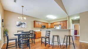 A modern kitchen with wooden cabinets, a central island, and bar stools. - Walk to The Strip: Family-friendly Branson Home (Branson)