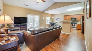 A living room with a brown leather sofa, a TV, and a ceiling fan. - Walk to The Strip: Family-friendly Branson Home (Branson)
