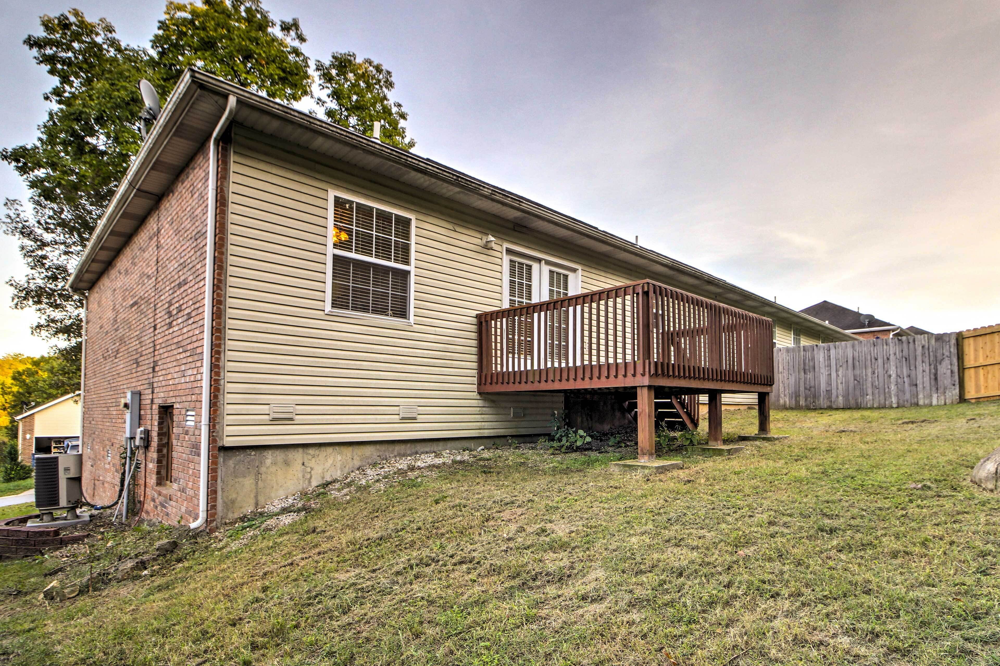 A single-story house with a wooden deck and a brick foundation.