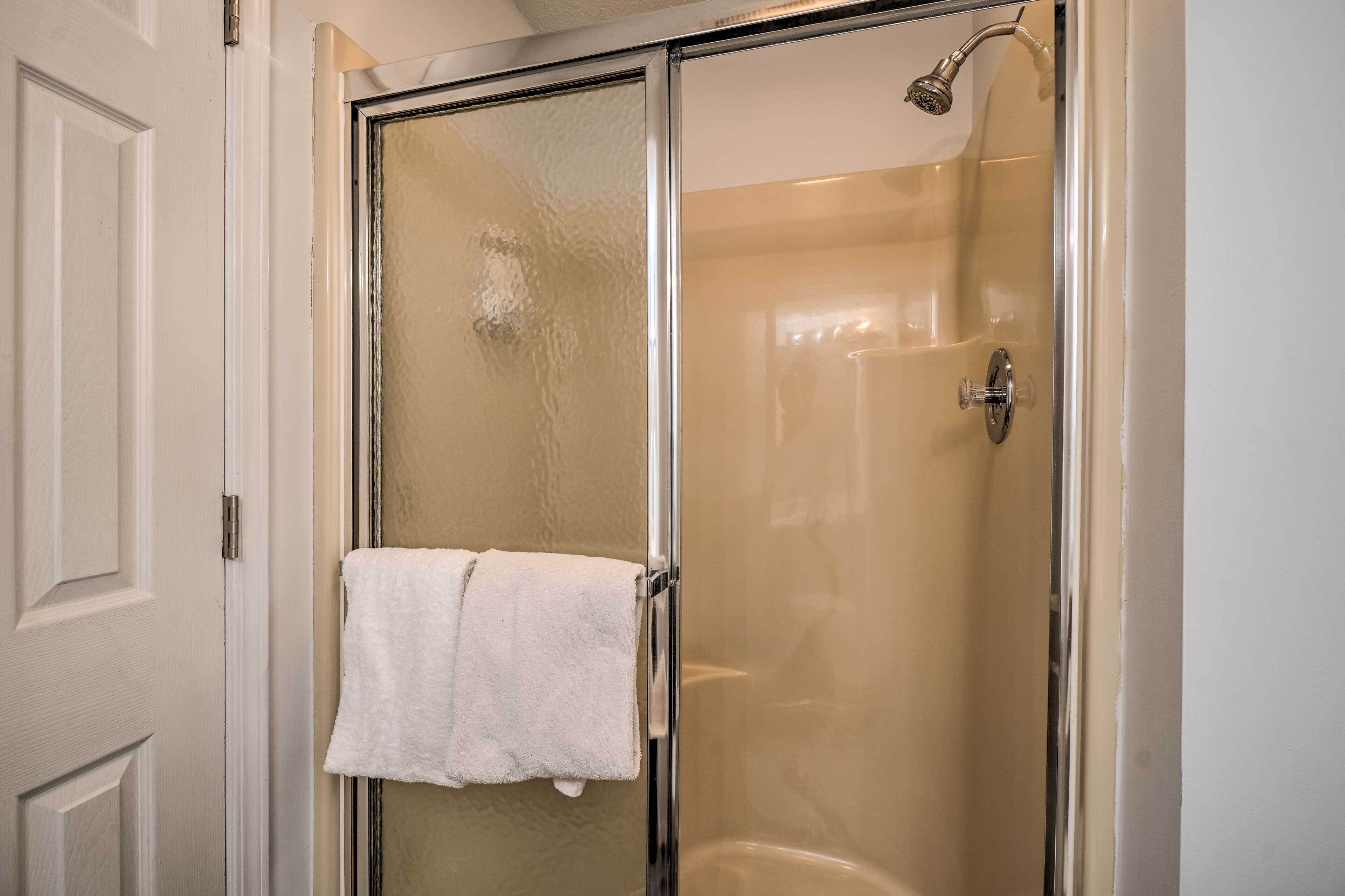 Cabina doccia in vetro con un asciugamano bianco appeso alla porta.