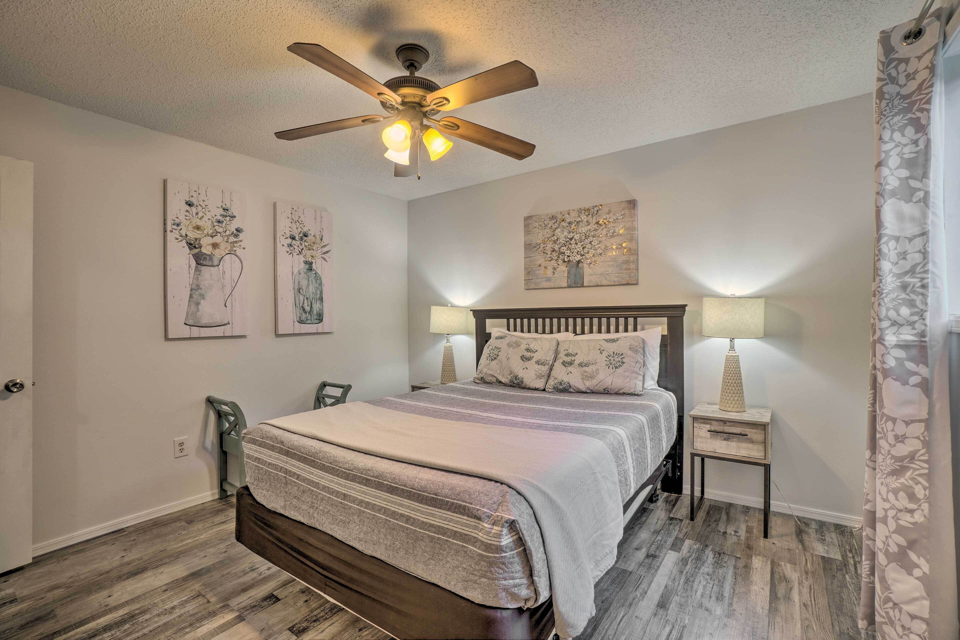 A bedroom with a bed, a ceiling fan, two wall-mounted lamps, and a nightstand.
