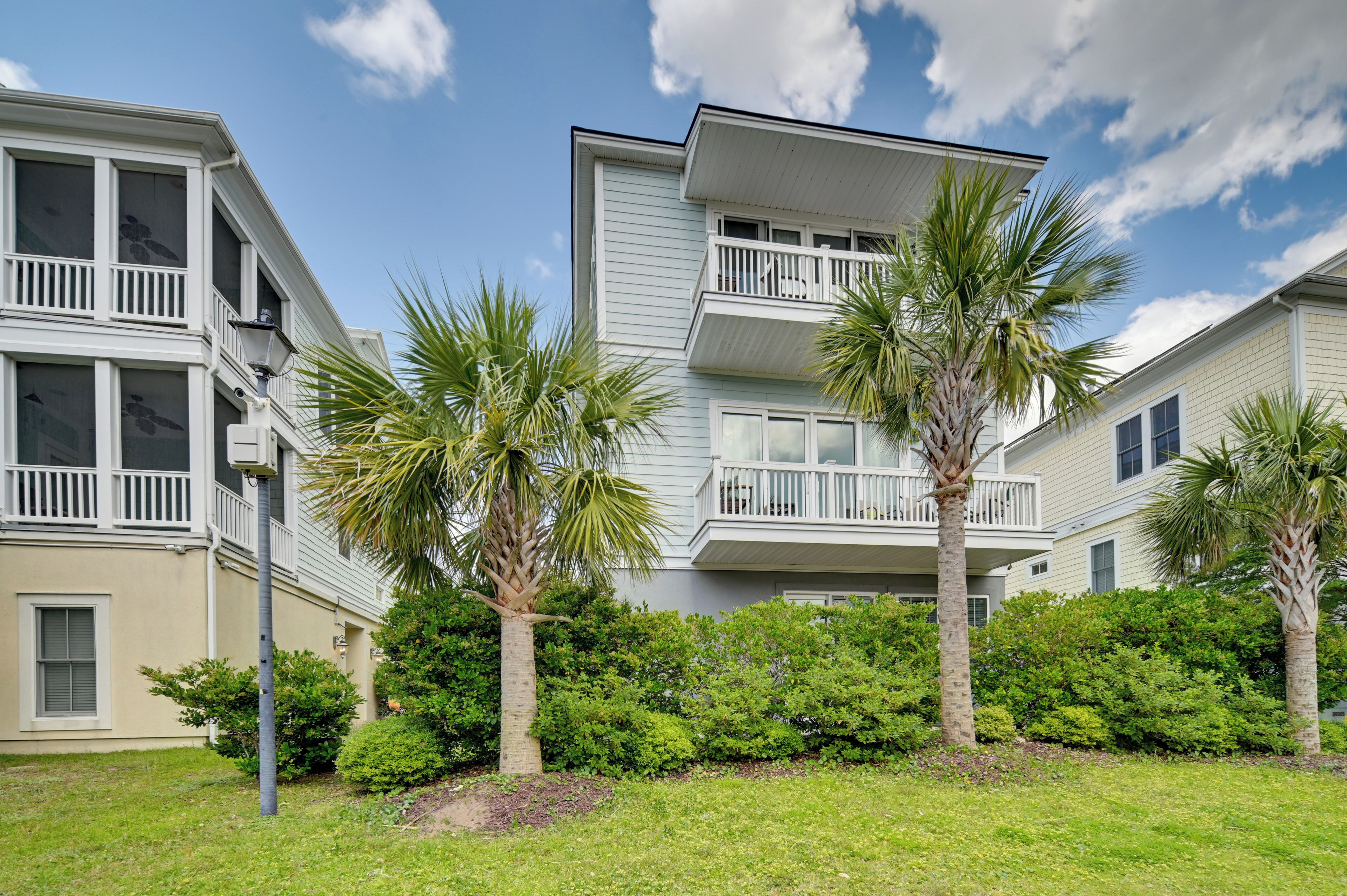 A multi-story residential building with balconies, surrounded by well-maintained lawns and palm trees.