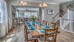 A dining area with a long wooden table set for a meal, surrounded by chairs. - 1 Block to Beach! Breezy Myrtle Beach Getaway (Myrtle Beach)