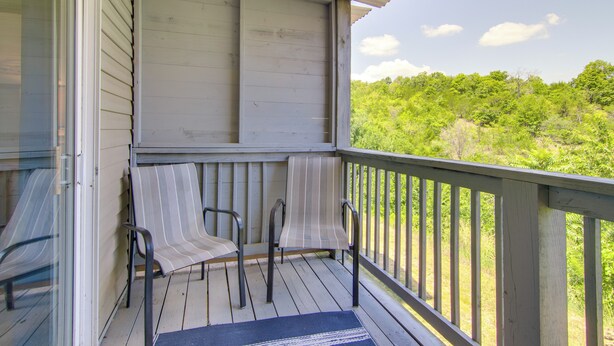 A wooden deck with two chairs and a rug, overlooking a green landscape. - Walk-in Unit, No Stairs, Pool! Family Fun Awaits (Branson)