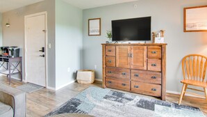 A living room with a wooden cabinet, a television, and a chair. - Walk-in Unit, No Stairs, Pool! Family Fun Awaits (Branson)