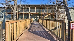 A wooden pedestrian bridge leading to a motel with a balcony and a sign indicating quiet hours. - Branson West Condo Rental w/ Pool Access! (Branson West)