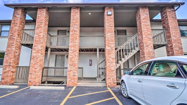 A building with brick columns, a covered entrance, and a car parked in front.