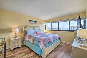 A bedroom with a bed, bedside tables, a window with a view, and a desk with a lamp.