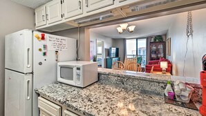 A kitchen with a microwave, cabinets, and a note on the fridge. - Bright Myrtle Beach Condo w/ Private Balcony! (Myrtle Beach)