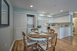 A modern kitchen with white cabinets, a central island, and a dining area with wooden chairs and a white table.