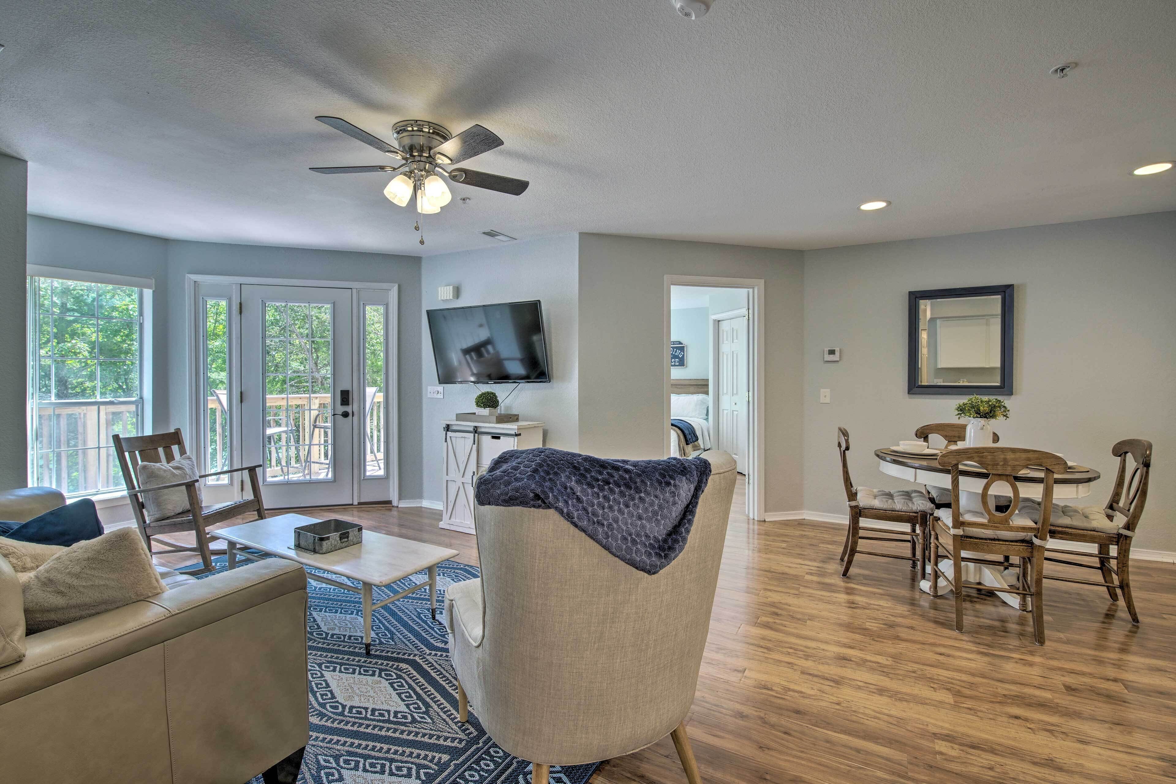 A spacious living room with a ceiling fan, a TV, and a dining area with a table and chairs.