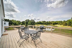 Una terraza con mobiliario exterior, una parrilla y vistas a un campo de golf y un lago.
