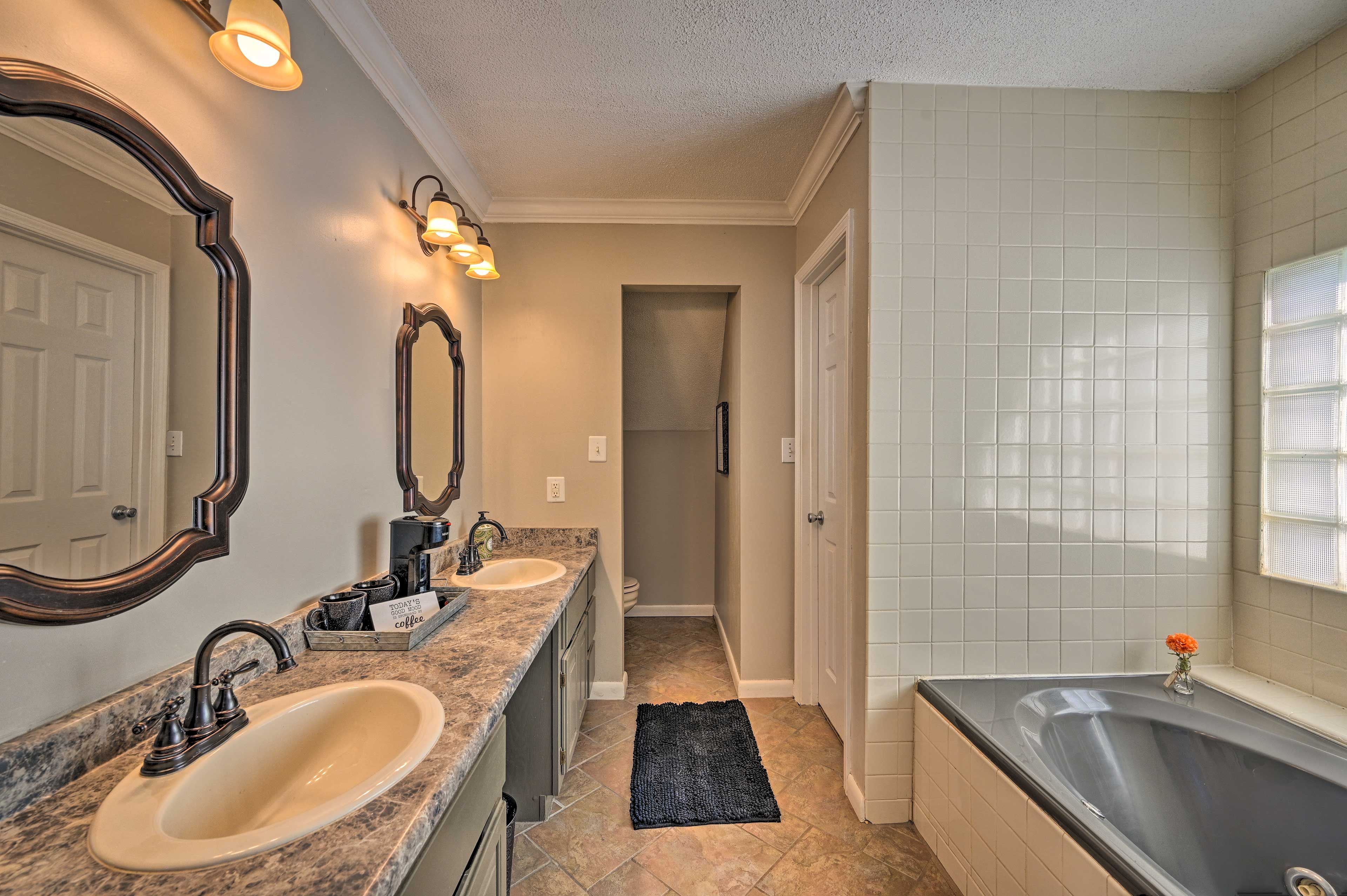 A bathroom with two sinks, a bathtub, and a mirror.