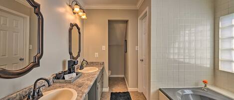 A bathroom with two sinks, a bathtub, and a mirror.