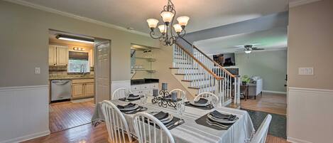A dining area with a chandelier, wooden chairs, and a table set for four.