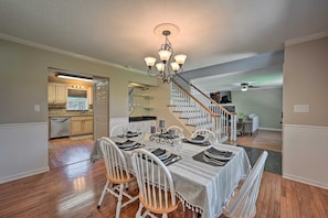 A dining area with a chandelier, wooden chairs, and a table set for four.
