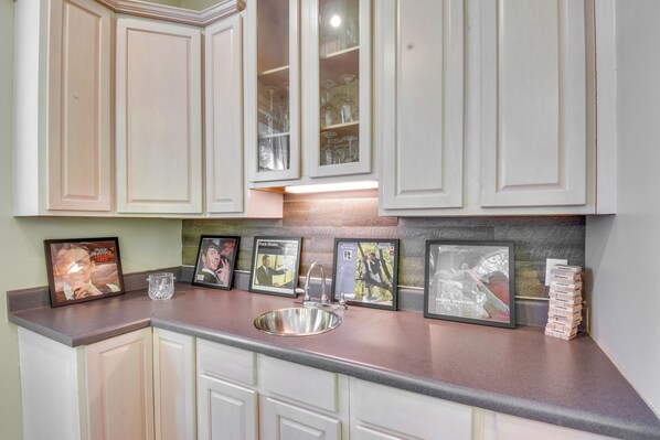A kitchen with white cabinets, a stainless steel sink, and framed pictures on the countertop. - 2 Mi to Clemson: Central Villa w/ Deck, Near Lakes (Clemson)