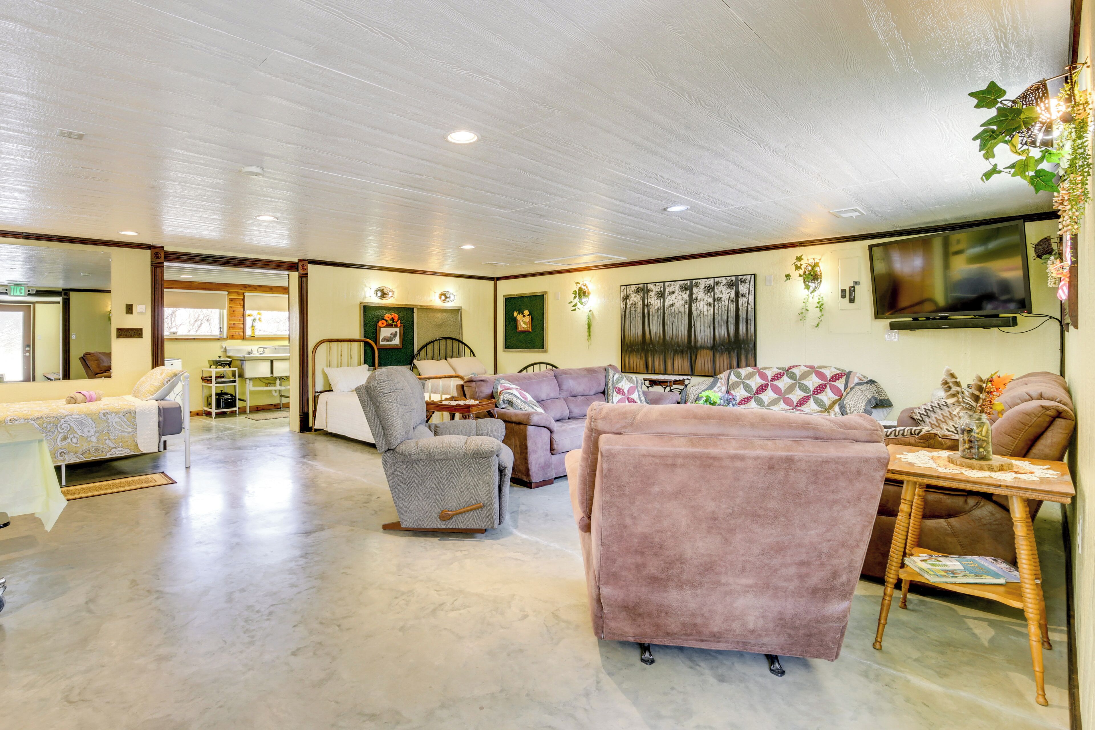 A spacious living room with a large sofa, armchairs, and a coffee table. There is a television mounted on the wall and a fireplace.