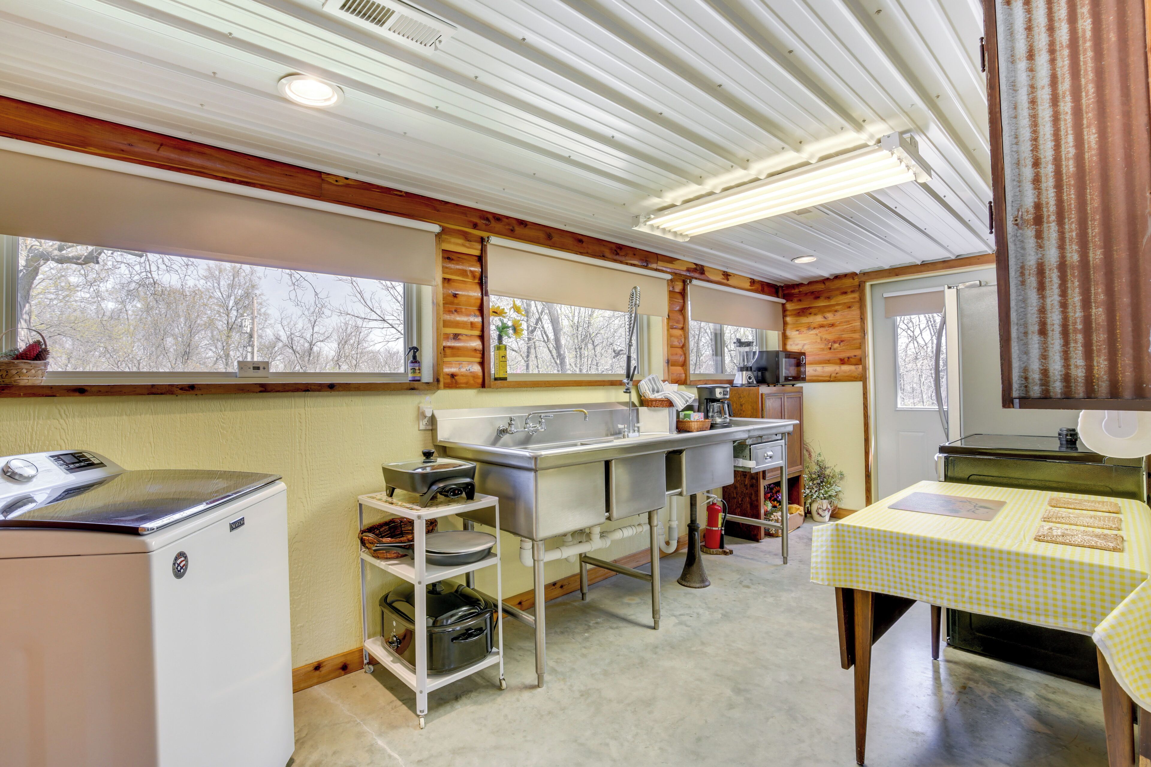 A compact kitchen with a refrigerator, sink, and a table with a checkered tablecloth.