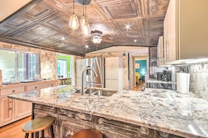 A kitchen with a large island, stainless steel appliances, and a rustic ceiling. - Cheery Swansea Home on Calmont Pond w/ Dock! (Swansea)