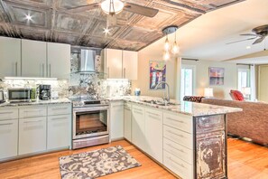 A modern kitchen with white cabinets, stainless steel appliances, and a marble countertop. - Cheery Swansea Home on Calmont Pond w/ Dock! (Swansea)