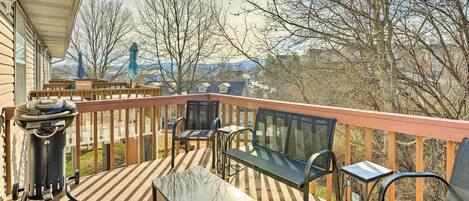 A covered outdoor deck with a barbecue grill, seating area, and a view of mountains.