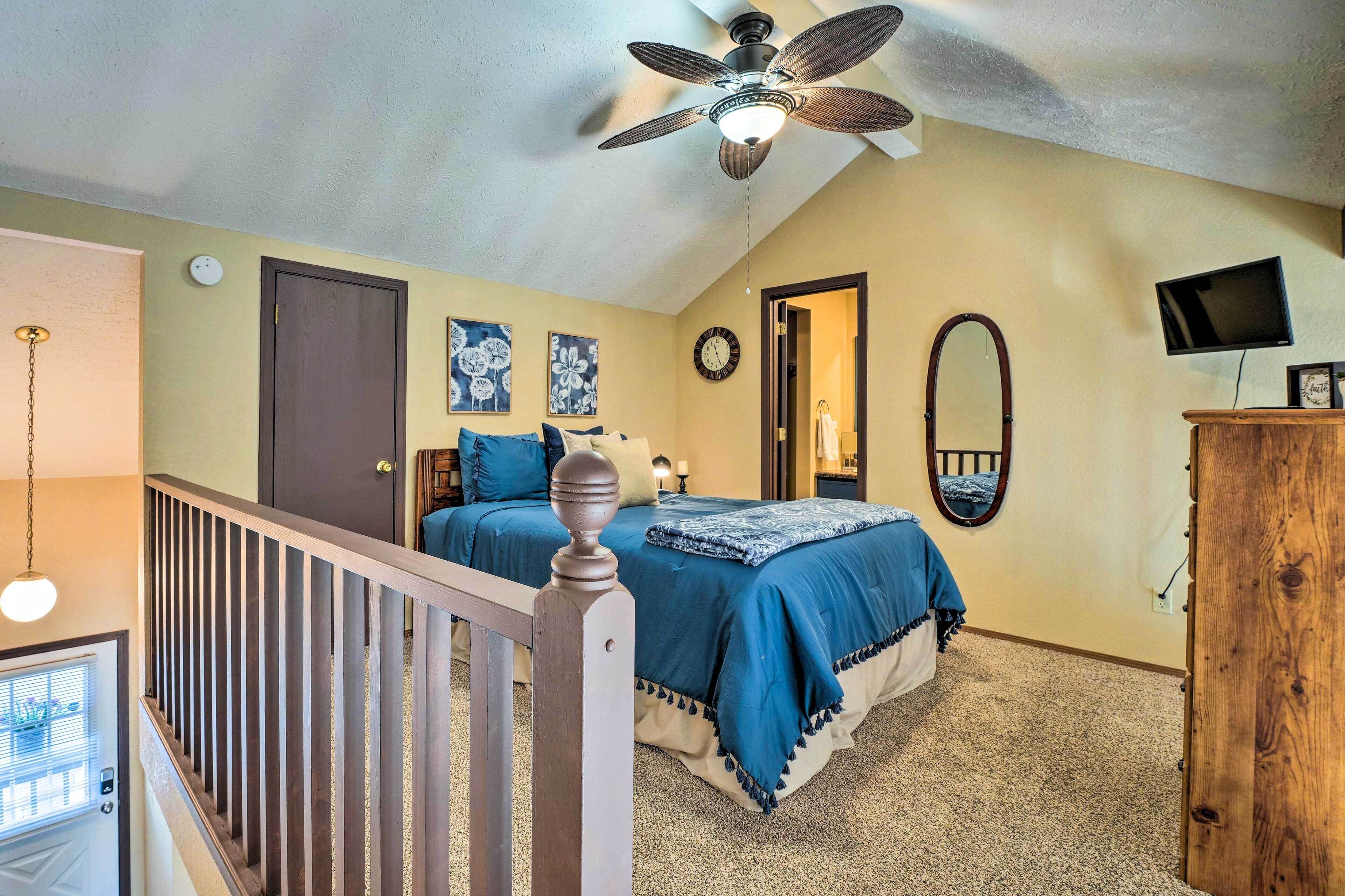 A bedroom with a bed, a ceiling fan, a TV, and a wooden dresser.